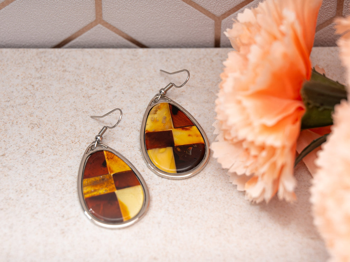 Baltic amber mosaic teardrop earrings beside peach flowers
