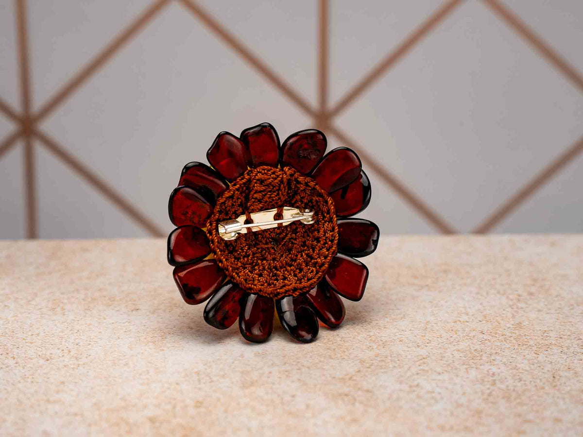 Back of the amber flower brooch and pendant with a thread-covered base and brooch pin.