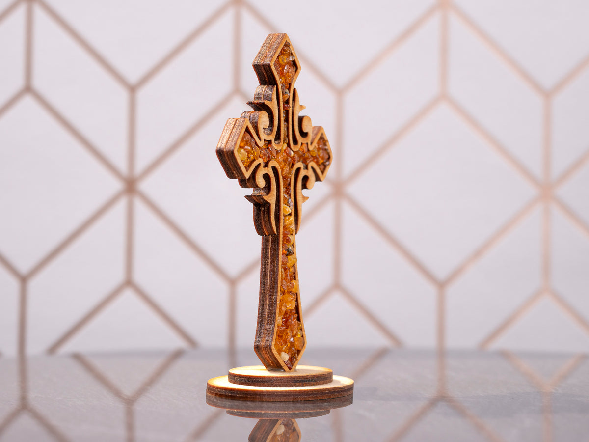 Standing wooden cross with amber pieces, side angle showing the layered wood construction and oval base.