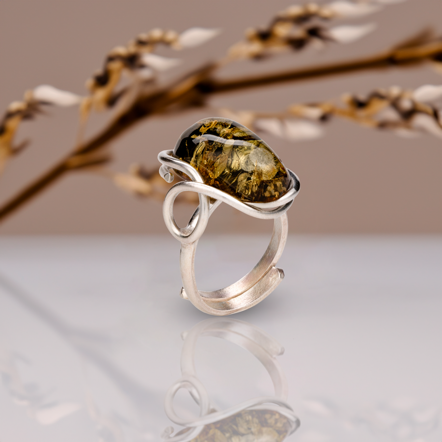 Angled view of the adjustable amber ring showing the domed cabochon, open band and loop-shaped detail