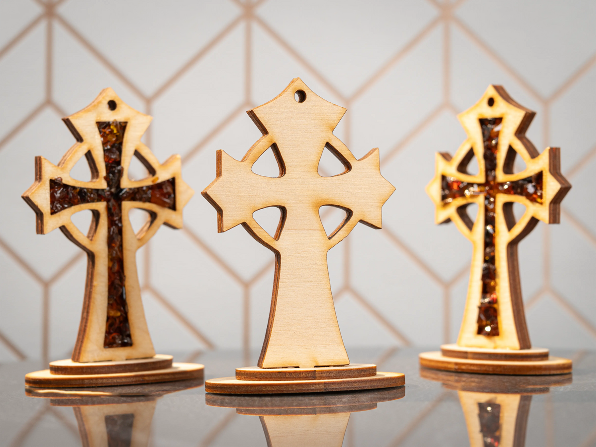 Three standing wooden crosses, with the centre showing its plain wood back and the two outer crosses showing amber-filled fronts.
