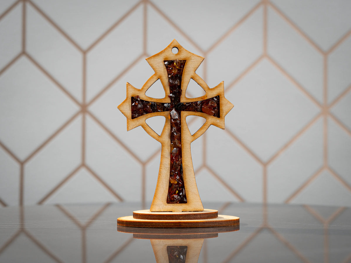 Standing wooden cross with dark-toned amber pieces, straight front view with cutout openings and an oval base.